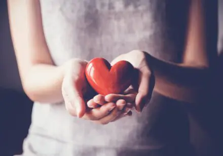 woman holding red heart made of polished wood