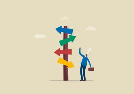 Cartoon illustration of man in a blue suit carrying a brown suitcase looking confused. He's standing at a sign that has four arrows going in different directions. The arrows are blue, green, red, and yellow, from the top to bottom respectively.