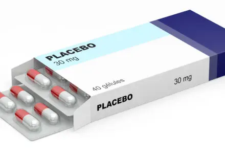 Box of Placebo tablets with writing on the box saying - Placebo 30mg. The box is partially opened and shows red-and-white capsules inside. The box is white with a sky blue bar across the length that highlights the word 'placebo' and a dark blue bar across the width at one end.