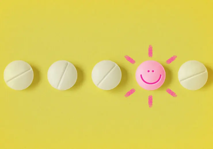 Row of five tablets in a horizontal row on a bright yellow background. Four of the tablets are pale yellow. The second from the right is bright pink, has a smiley face, and sunshine emanations coming out of it.