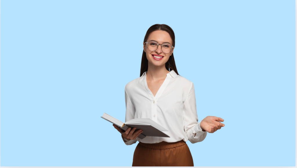 Young woman with long dark brown hair tied back, wearing large circular rimmed glasses, a white blue, and light brown trousers holding an open book with the other hand open, as if explaining something. The background is light blue.