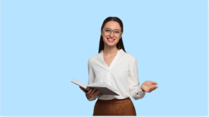 Young woman with long dark brown hair tied back, wearing large circular rimmed glasses, a white blue, and light brown trousers holding an open book with the other hand open, as if explaining something. The background is light blue.