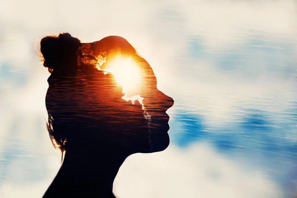 Silhouette of young woman on sky background with sun inside her head.