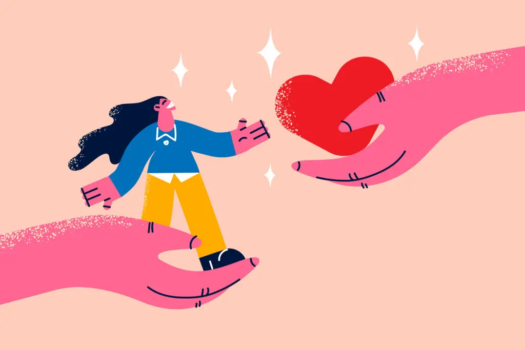 Kindness as a superfood concept. Large pink cartoon hands, one holding a woman with long flowing dark hair, a red blouse and yellow trousers, the other holding a red heart. The background is peach and there's twinkling stars.