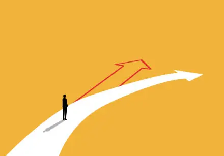 Novelty. Man standing on a large white arrow that bends to the right. The route ahead is a red arrow. The image suggests that we can choose something different. The background is mustard yellow.