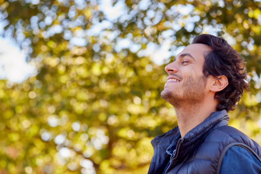 Illustration of flow. Man looking genuinely happy against a blurred background of trees on am autumn day.