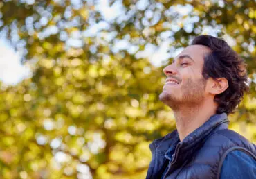 Illustration of flow. Man looking genuinely happy against a blurred background of trees on am autumn day.