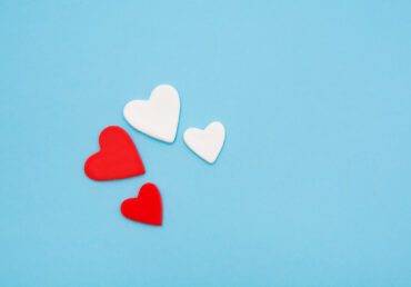 Two red and two white hearts on a pastel blue background.