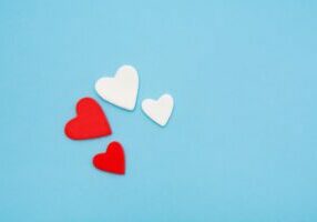 Two red and two white hearts on a pastel blue background.